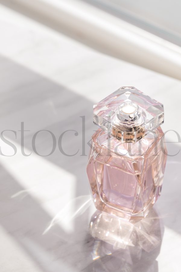 Vertical stock photo of pink perfume bottle