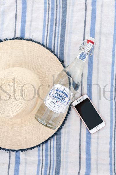 Vertical Stock photo of beach towel, hat, bottle and phone