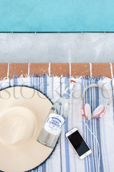 Vertical Stock photo of beach towel, hat, bottle and phone