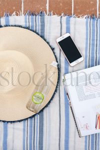 Vertical Stock photo of beach towel, hat, bottle and phone