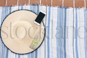 Horizontal Stock photo of beach towel, hat, bottle and phone