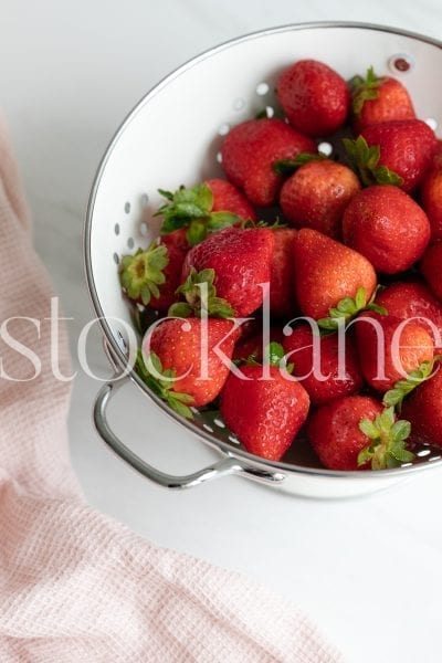 Vertical stock photo of strawberries in colander