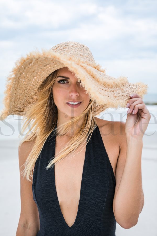 Vertical stock photo of woman at the beach with large hat