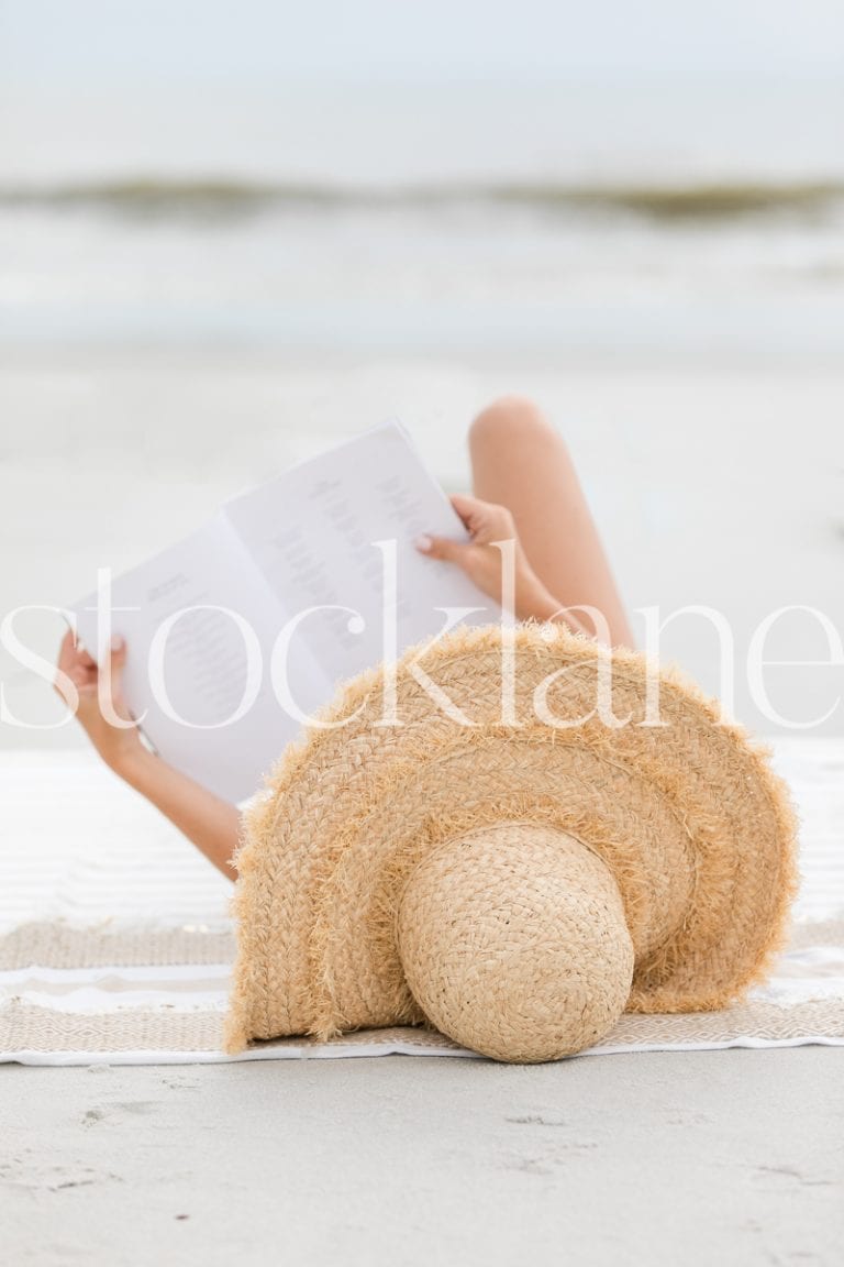 Vertical stock photo of woman reading at the beach