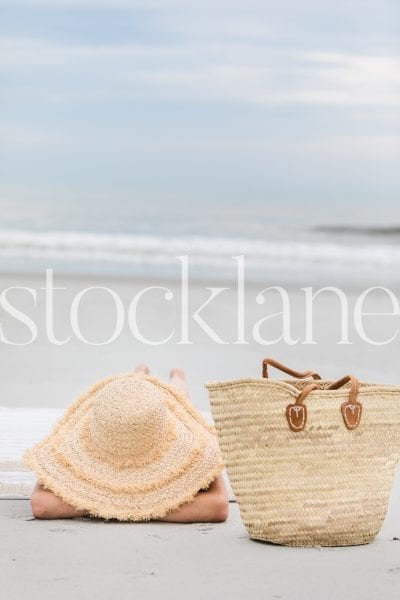 Vertical stock photo of woman with large hat at the beach