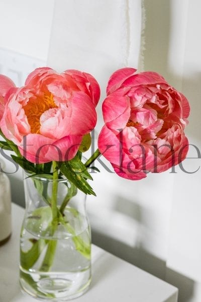 Vertical photo of peonies in a vase in a bathroom