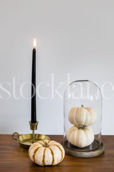 Vertical stock photo of white pumpkins and black candle