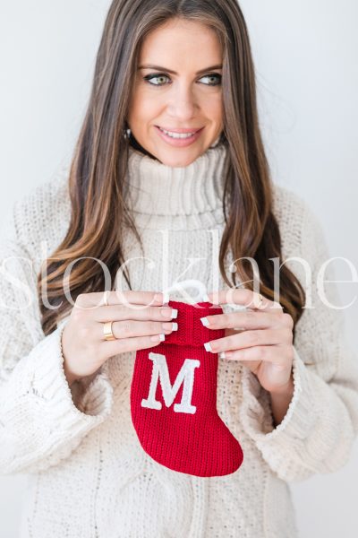 Vertical stock photo of woman holding small Christmas stocking