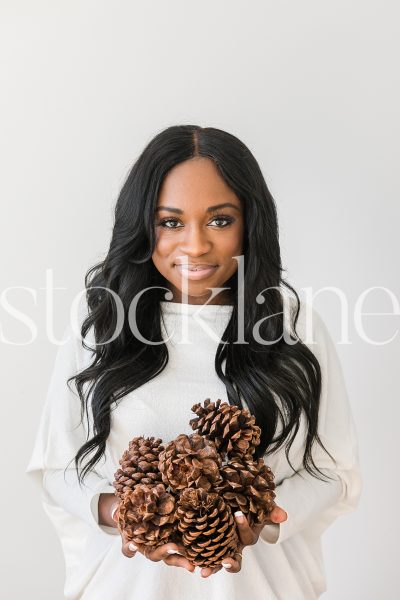 Vertical stock photo of woman holding pine cones