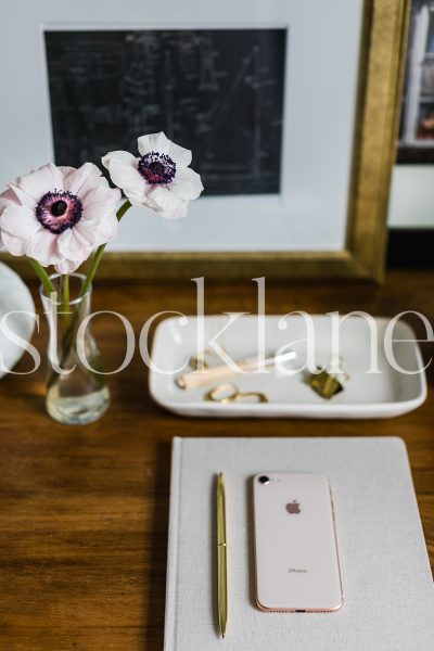 Vertical stock photo of desk with notebook and flowers