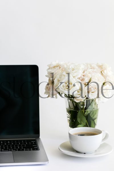 Vertical stock photo of computer with coffee and roses