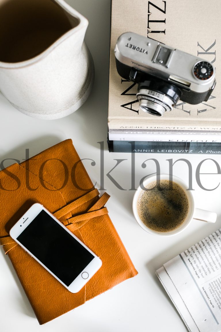 Vertical stock photo of desktop with coffee, camera and newspaper