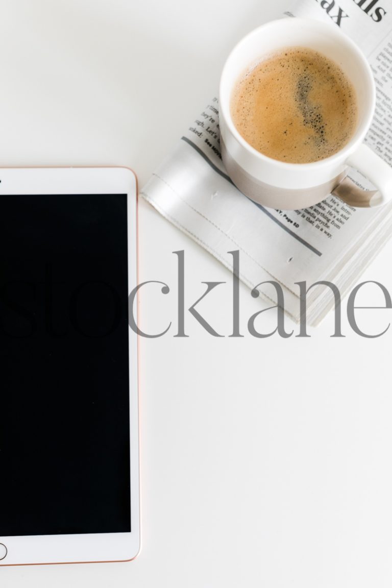 Vertical stock photo of ipad with coffee and newspaper