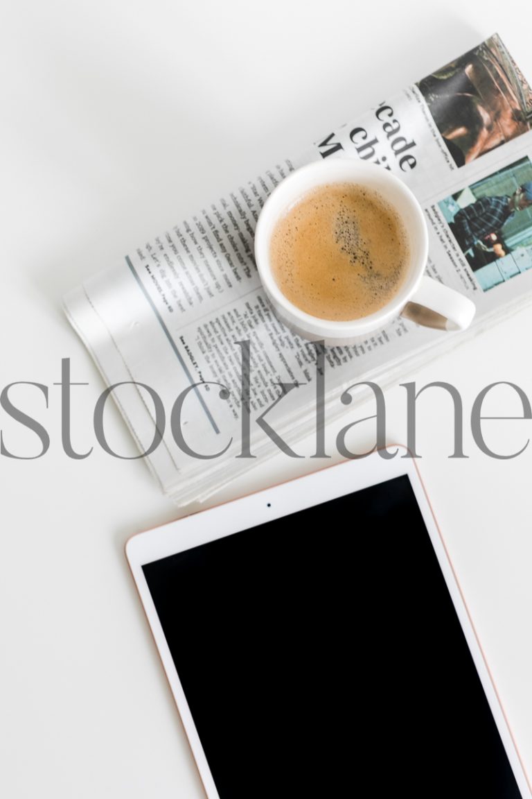 Vertical stock photo of iPad with coffee and newspaper