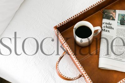 Horizontal stock photo of a bed with a tray with coffee and newspaper