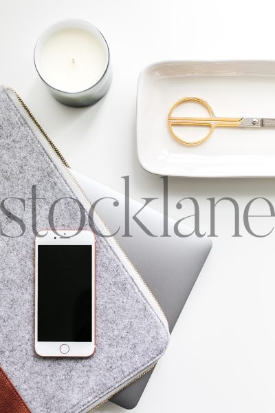 Vertical stock photo of laptop and iPhone on desk