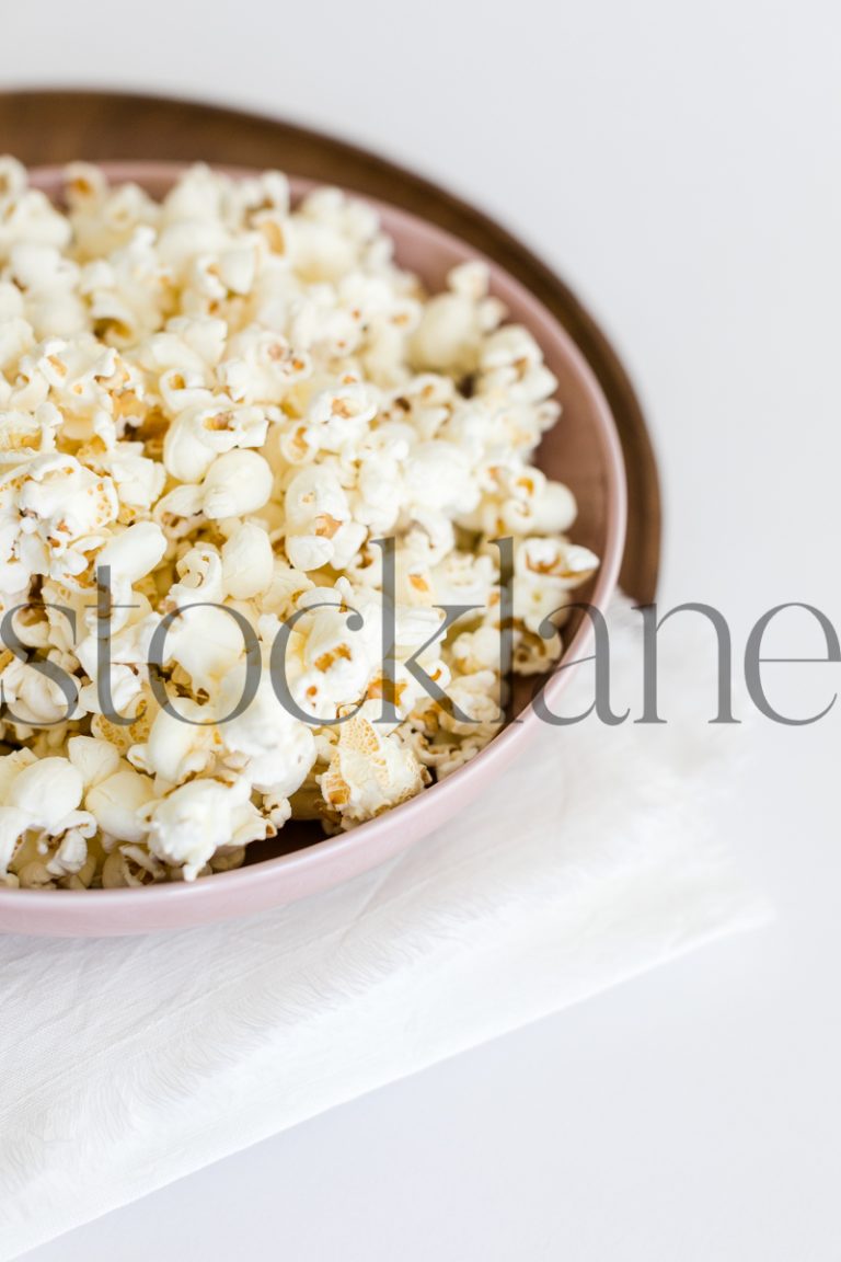 Vertical stock photo of pink bowl with popcorn