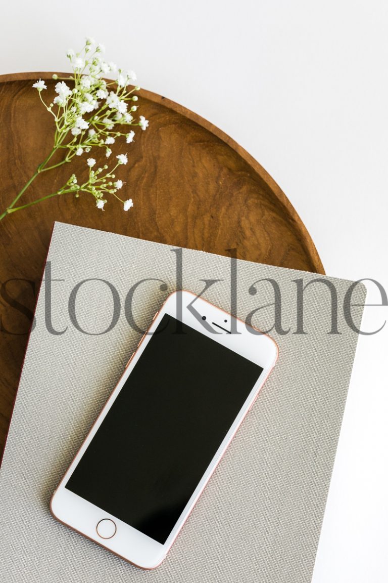 Vertical stock photo of iPhone and notebook on wood tray