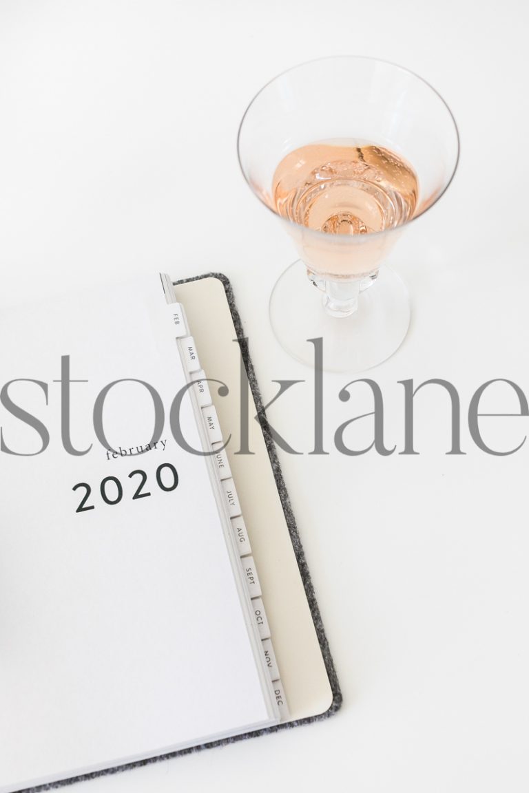 Vertical stock photo of planner and glass of wine