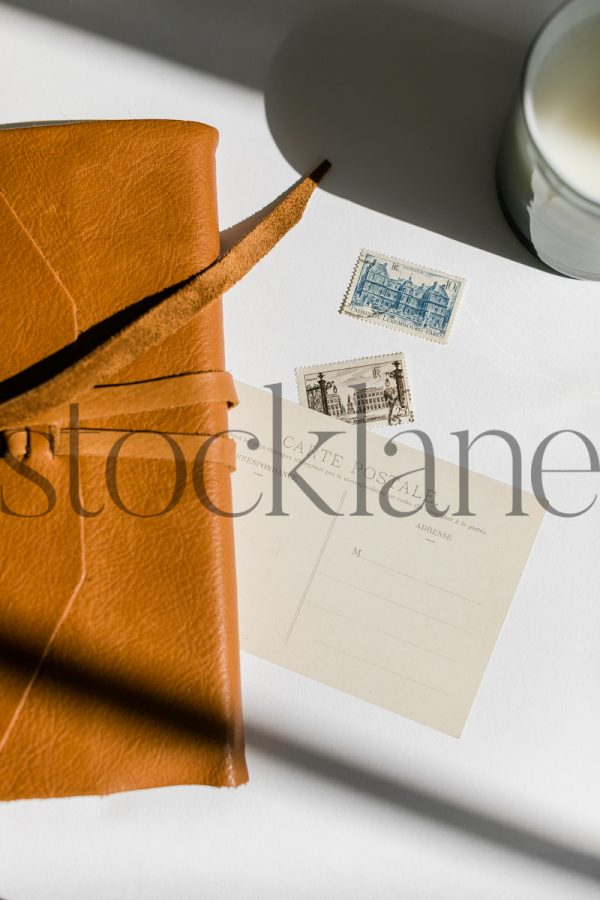 Vertical stock photo of leather journal and vintage postcard