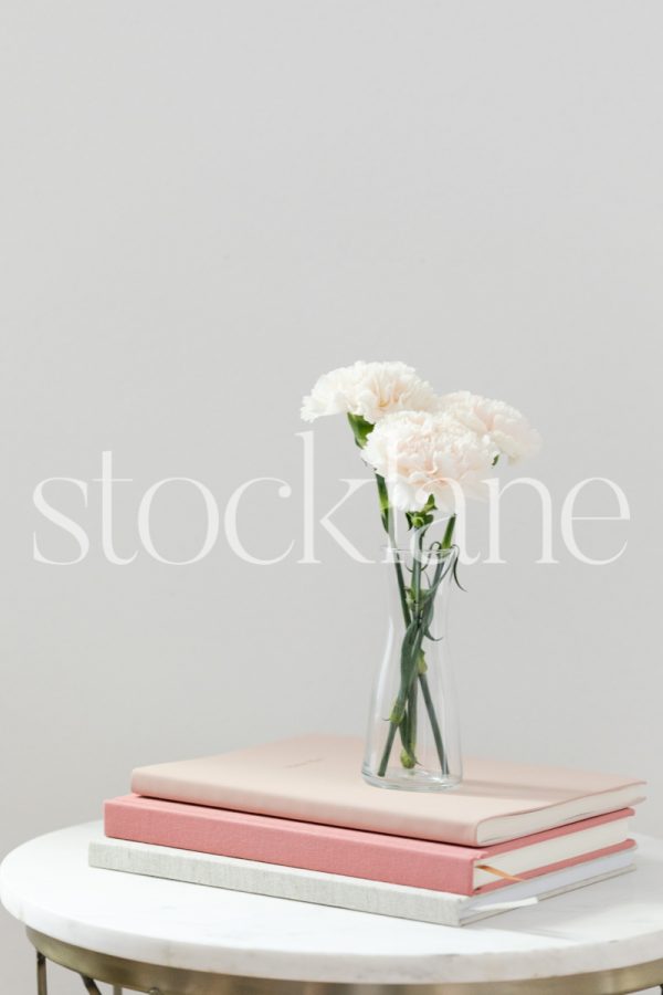 Vertical stock photo of pink notebooks and flowers