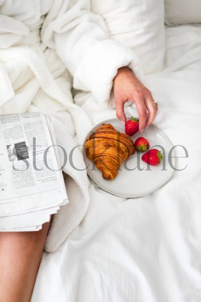 Vertical stock photo of woman having breakfast in bed