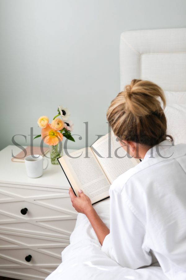 Vertical stock photo of woman reading in bed