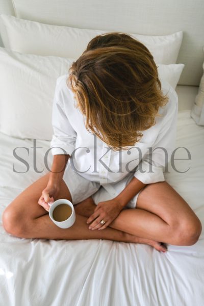 Vertical stock photo of woman having coffee in bed