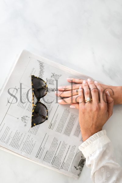 Vertical stock photo of woman's hands on newspaper