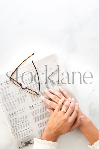 Vertical stock photo of woman's hands on newspaper