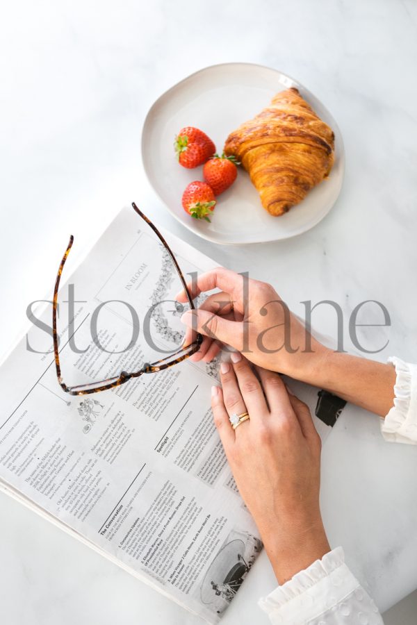 Vertical stock photo of woman's hands and newspaper