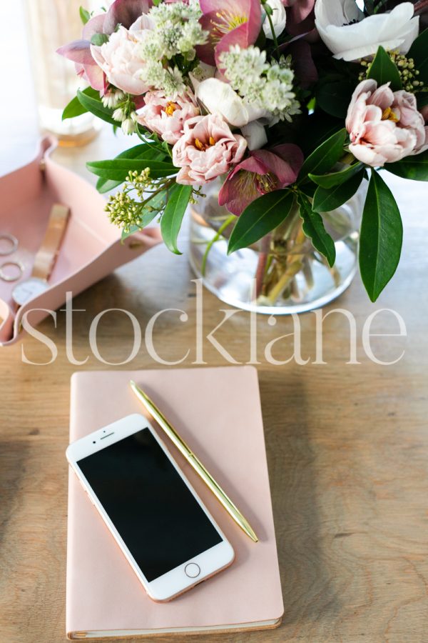 Vertical stock photo of phone and pink notebook