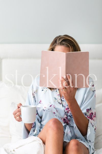 Vertical stock photo of woman reading in bed