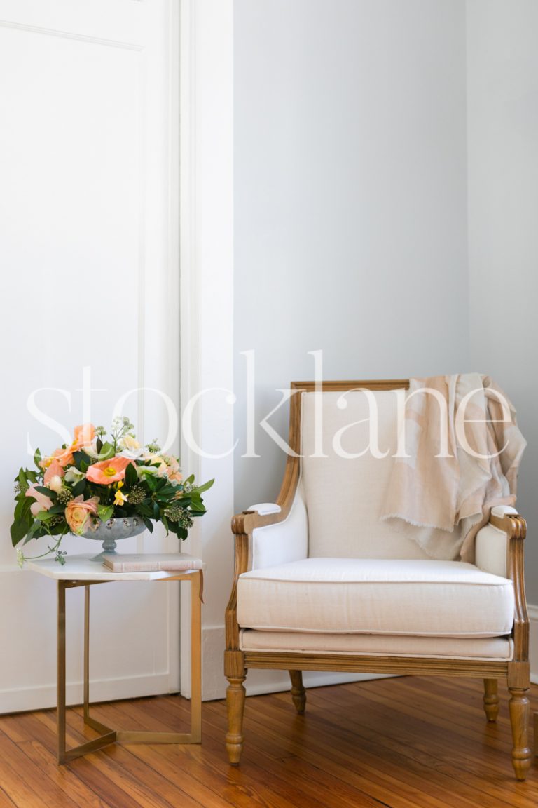 Vertical stock photo of reading chair and side table with flowers