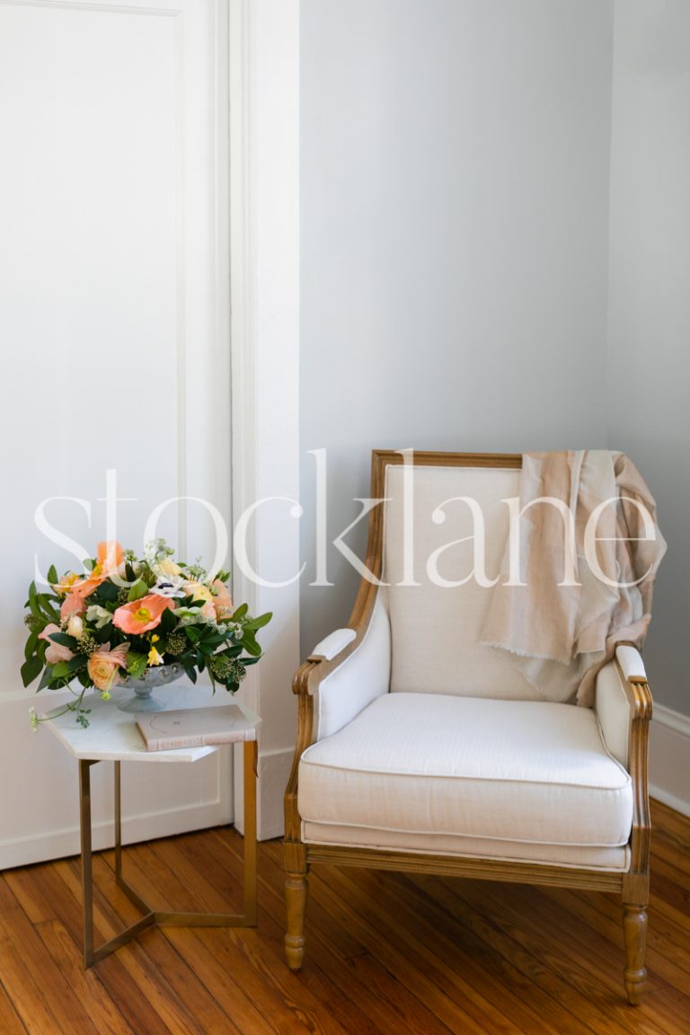 Vertical stock photo of reading chair and side table with flowers