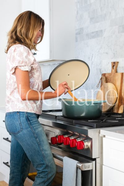 Vertical stock photo of woman cooking in stylish kitchen