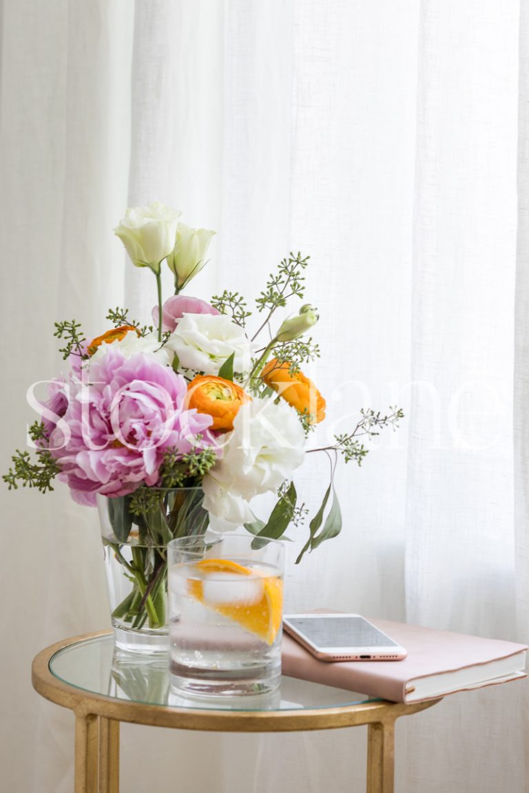 Vertical stock photo of table with drink, flowers and notebook