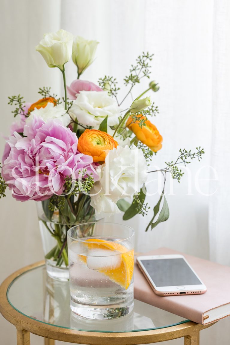 Vertical stock photo of table with drink, flowers and notebook