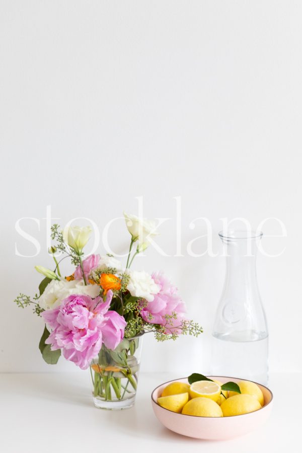 Vertical stock photo of table with flowers and bowl of lemons