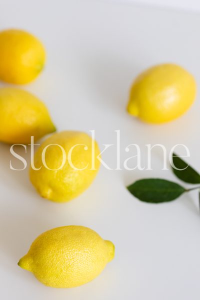 Vertical stock photo of lemons on a white background.