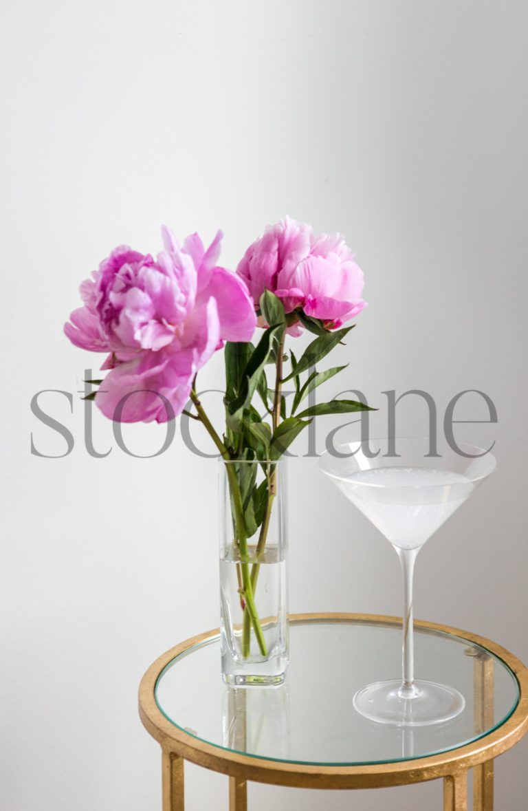 Vertical stock photo of martini drink with pink peonies.