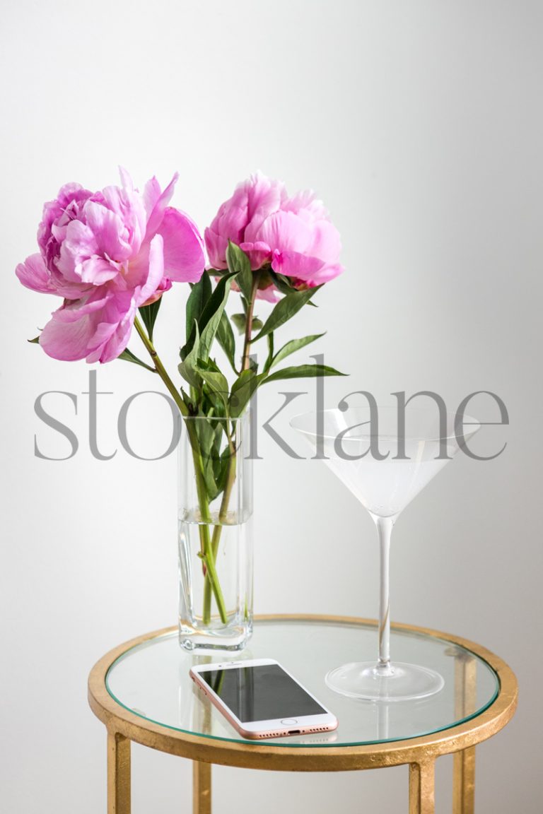 Vertical stock photo of martini drink with pink peonies.