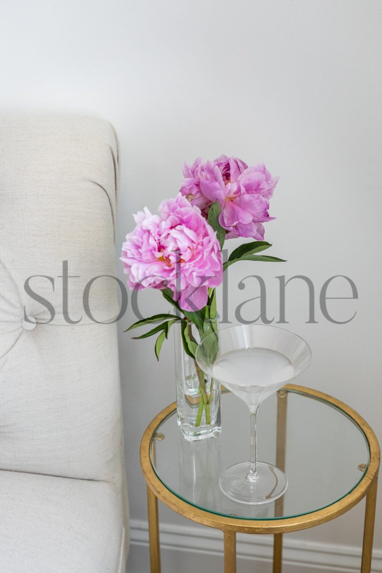 Vertical stock photo of martini drink with pink peonies.