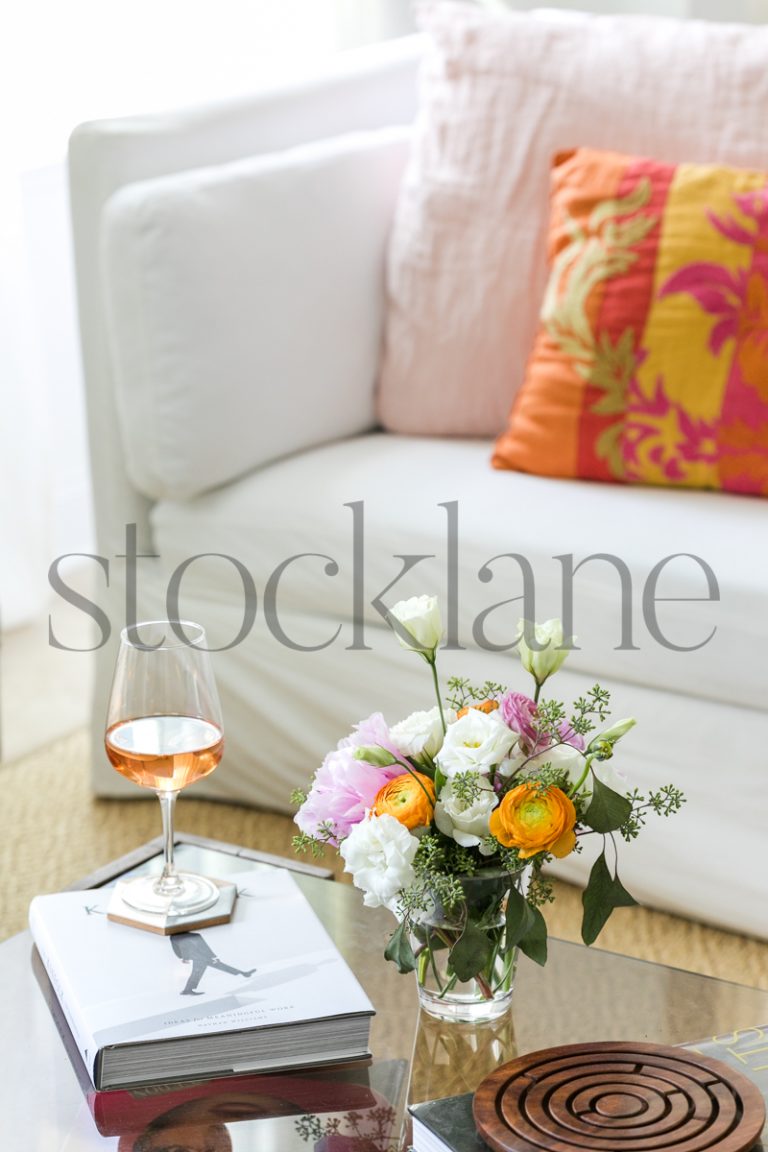 Vertical stock photo of coffee table with rose wine and flower arrangement