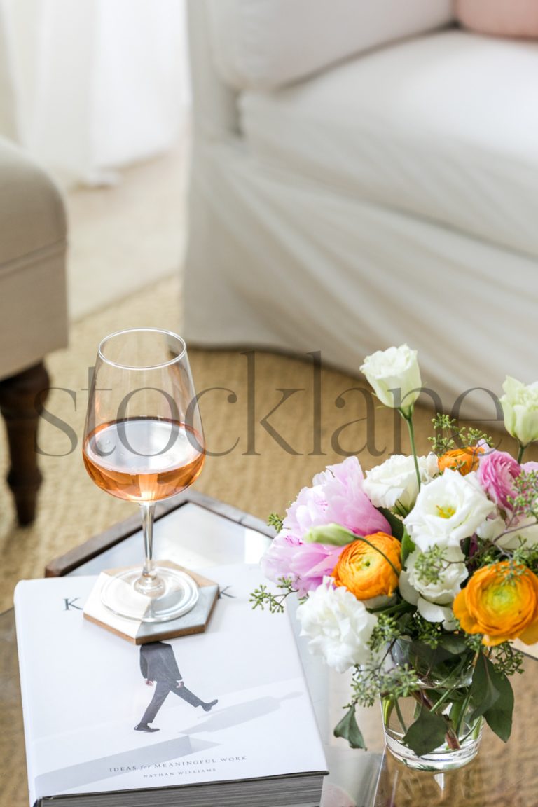 Vertical stock photo of coffee table with rose wine and flower arrangement