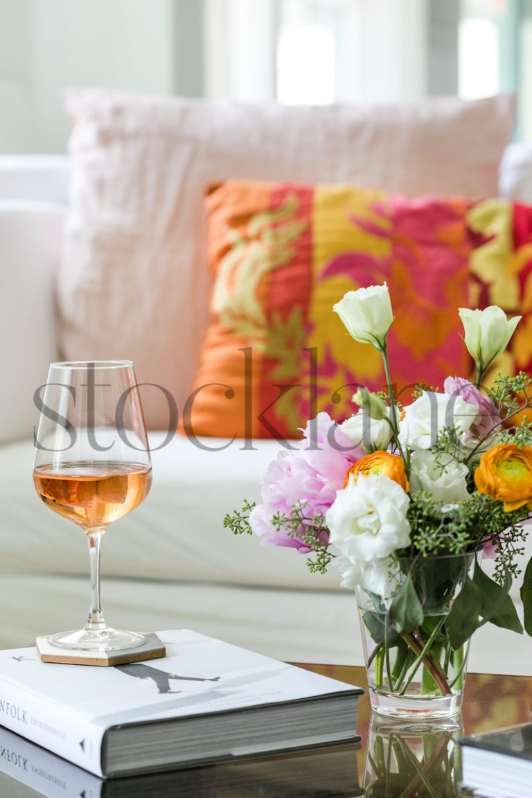 Vertical stock photo of coffee table with rose wine and flower arrangement