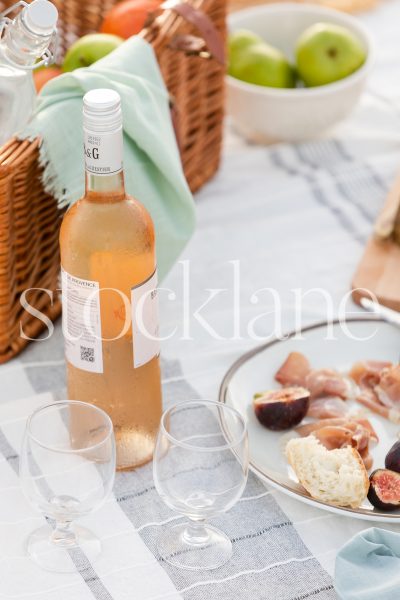 Vertical stock photo of summer beach picnic with rose, figs and prosciutto.