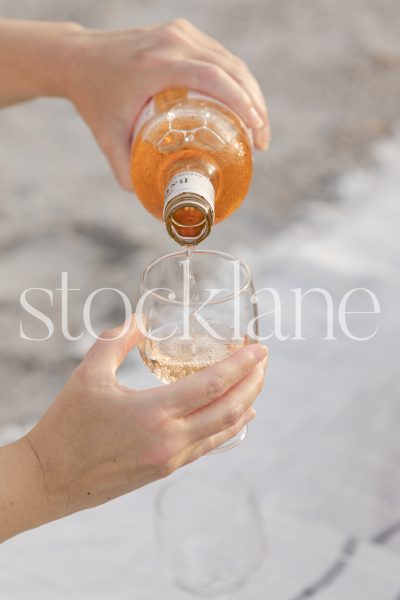 Vertical stock photo of woman pouring rose wine.