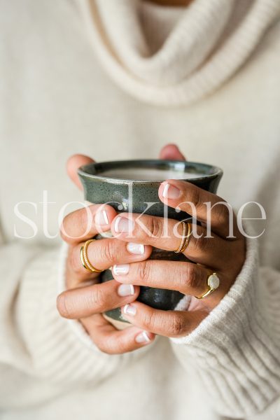 Vertical stock photo of woman holding coffee cup.