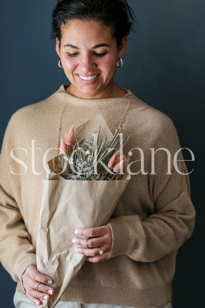 Vertical stock photo of a woman holding a fall bouquet.